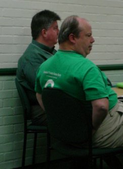 Two guys in green shirts sit.