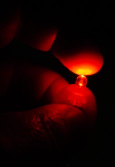 Orange LED shines on a finger tip in the dark.