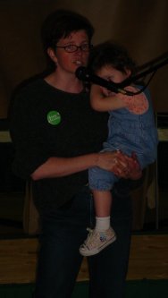 Woman holds a child and speaks into the microphone.