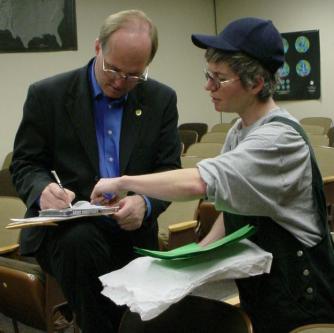 Cobb writes something down for a woman who is organizing the UC Hayward Campus Greens.