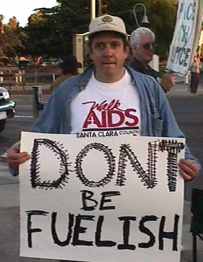 Tian holds a sign that says DONT BE FUELISH.