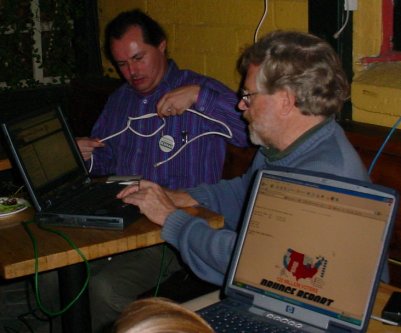 Cameron plays with the network wires while Gerry checks something on the screen.
