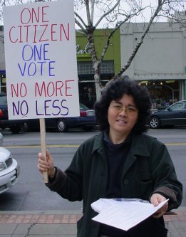 Woman with a sign that reads "ONE CITIZEN ONE VOTE, NO MORE NO LESS".