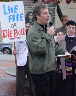 Peter Speaks with "LIVE FREE OR DIEBOLD" sign in background.