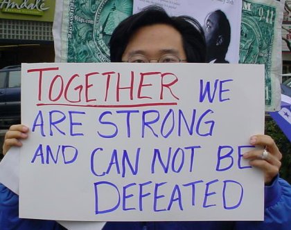 Guy holds sign that reads "Together we are strong and can not be defeated".