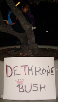 Child plays in a tree above a DETHRONE BUSH sign.