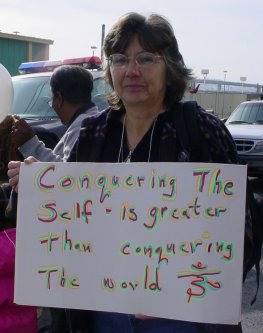 Woman holds a sign that says "conquering the self is a greater accomplishment than conquering Iraq."