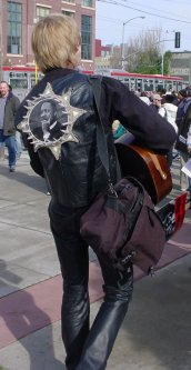 Man plays guitar with a picture of Martin Luther King on his back.