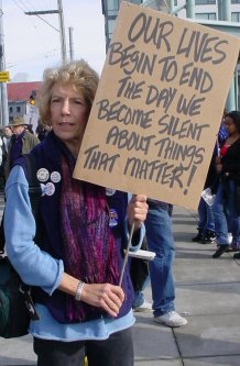 A woman holds a sign that says we must speak out about things that matter.