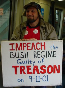 Smiling guy holds a sign that says "Impeach Bush for Treason".