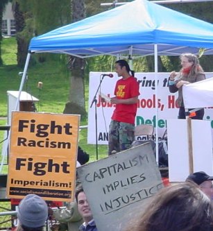 Speakers tent, in front of which is an orange sign that says "FIGHT RACISM FIGHT IMPERIALISM".