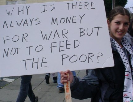 Woman with a sign that asks about the relationship between money and the poor
