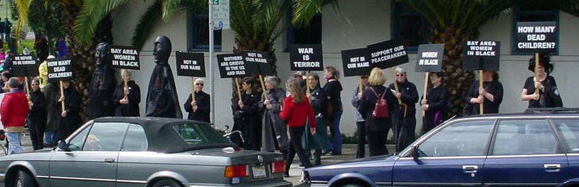 A row of women in black, many with signs.