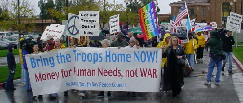 Banner at the front of the march reads "BRING THE TROOPS HOME NOW".