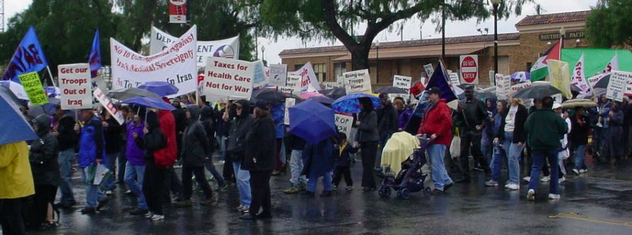A huge crowd of marchers in the rain at the train station, all ready to head out.