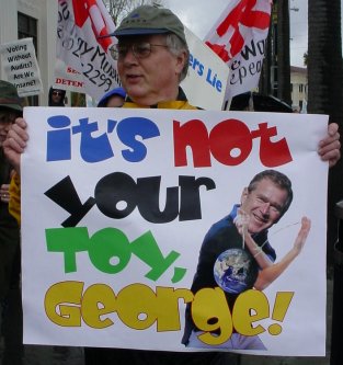 Man with a sign that says "It's not your toy George".