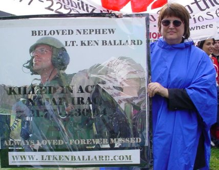 Woman stands with picture of fallen soldier.