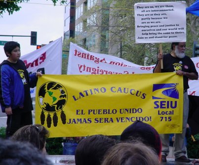 A youngster and a grandfather type hold a Latino Caucus banner from SEIU.