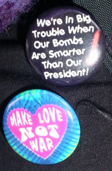 A pair of great buttons. The top on says "we're in big trouble when our bombs are smarter than our President." The other says "MAKE LOVE NOT WAR".