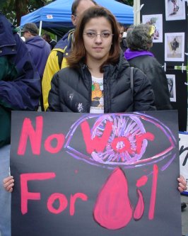 A sign that says NO WAR FOR OIL held by an attractive young woman.