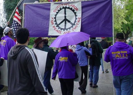 Union contingent in purple with a peace sign on their banner.