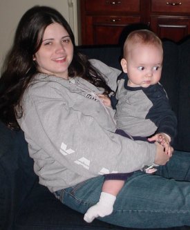Mother and son sit on couch smiling.