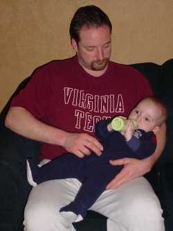 My brother in a Virginia shirt feeding his son.